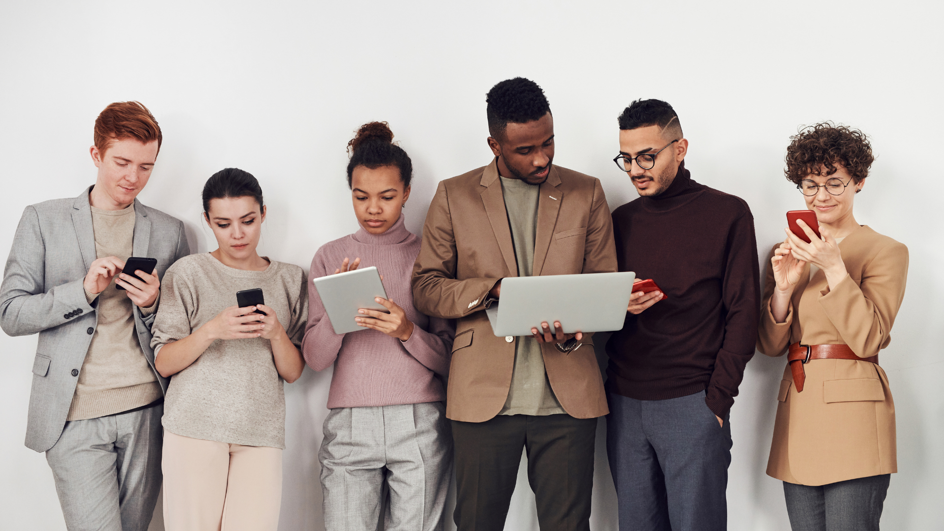 Six people looking at either phones, Ipads or laptops.